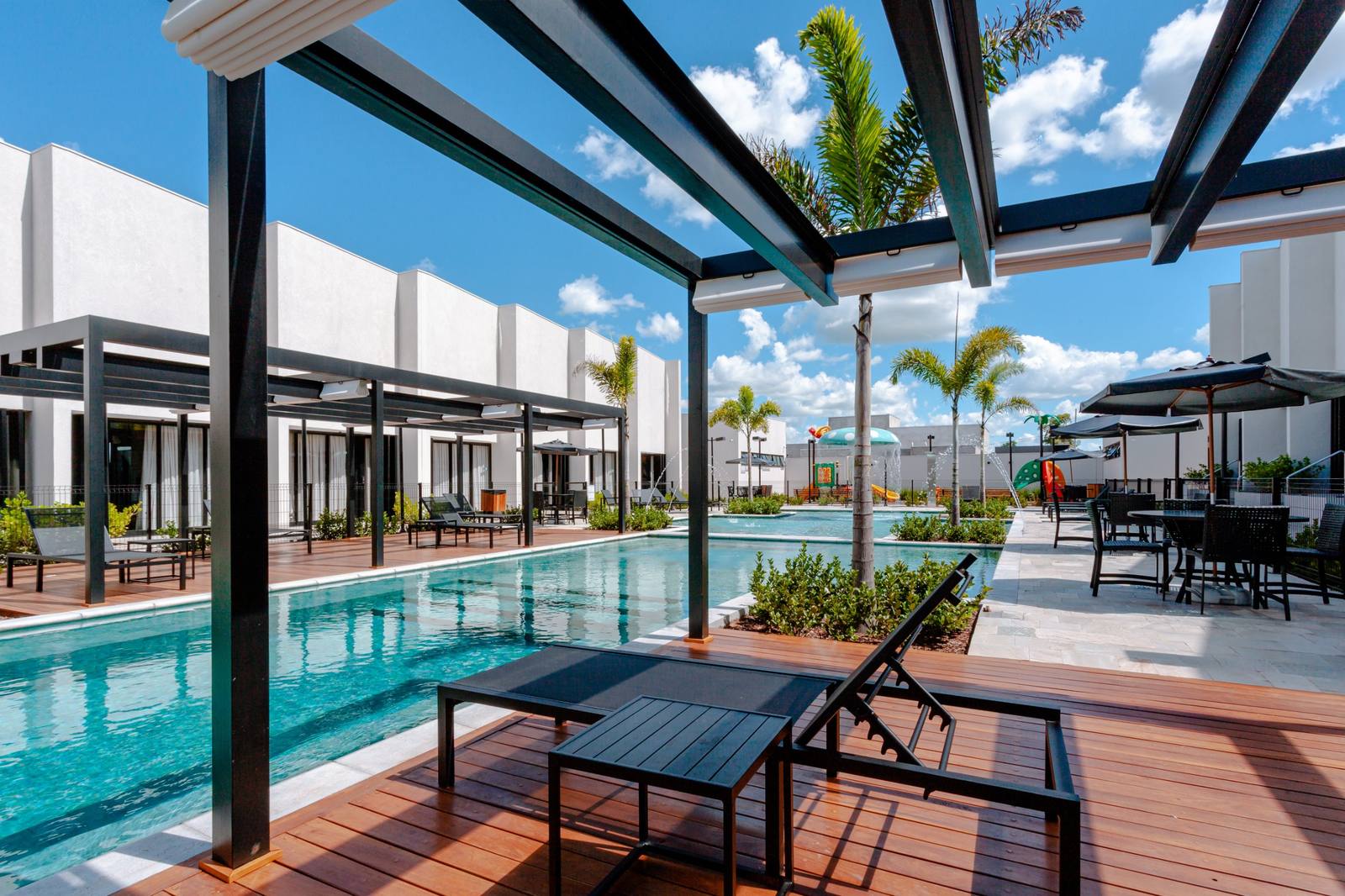 Deck de madeira com pergolado e espreguiçadeiras ao lado da piscina