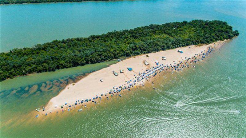 Praia de areia no meio do rio, com barcos ancorados